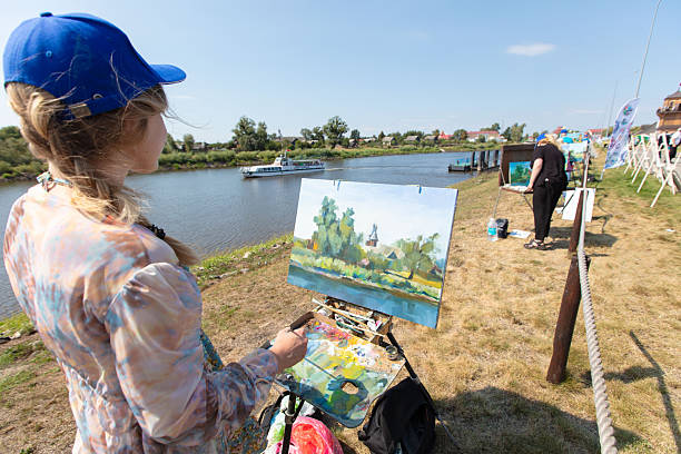 Woman painting a landscape outdoors with an easel surrounded by nature – art in nature, outdoor hobbies for women