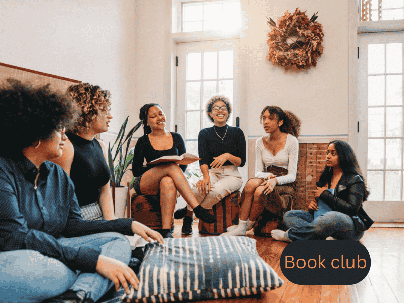 Group of women in their 30s discussing a novel at a cozy book club gathering