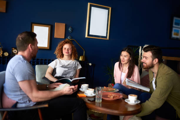 Multiethnic group of people in coffee shop having food and drinks while reading some books and talking.