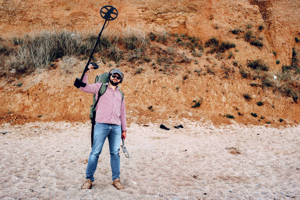 Happy Male with metal detector found something on the beach