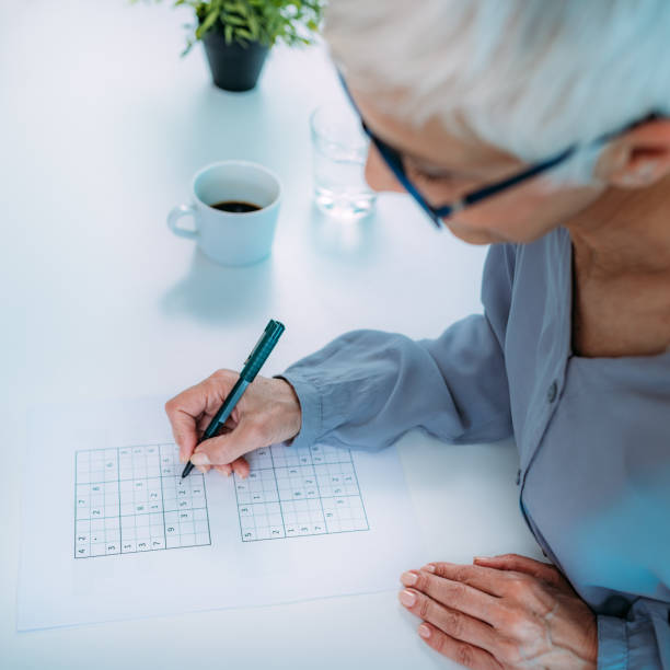 Cognitive training. Senior woman solving sudoku puzzles.