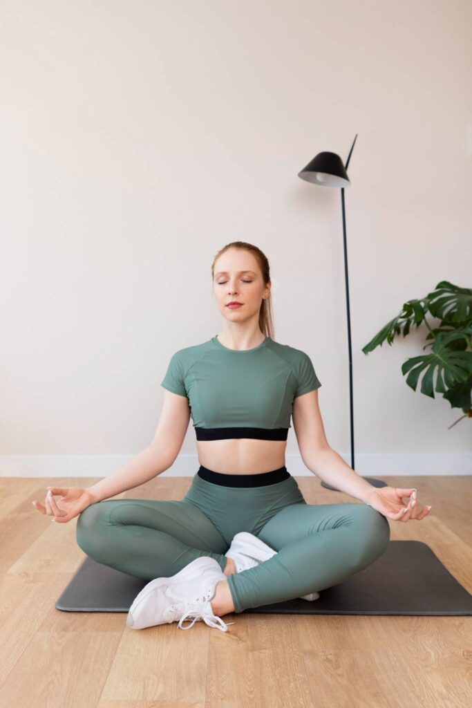 Woman practicing meditation in a seated yoga pose at home — a calming solo hobby for women to enhance mindfulness and relaxation.