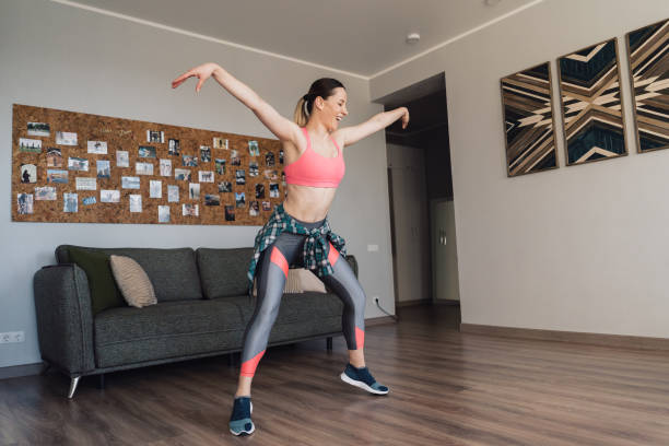 Woman doing a fun dance workout routine at home in a bright living room