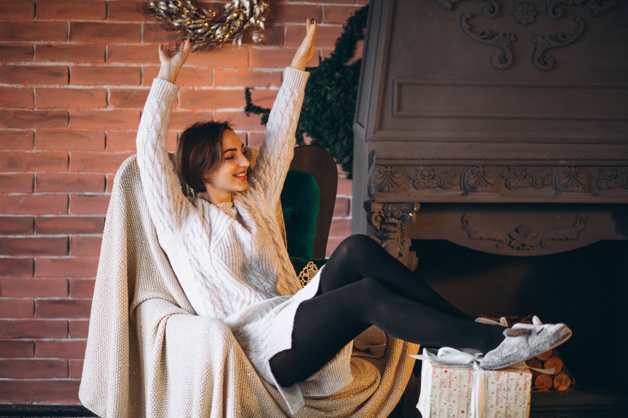 A woman enjoying a cozy and relaxing morning routine, smiling and stretching in a warm room — symbolizing morning routine ideas that make you excited to wake up.