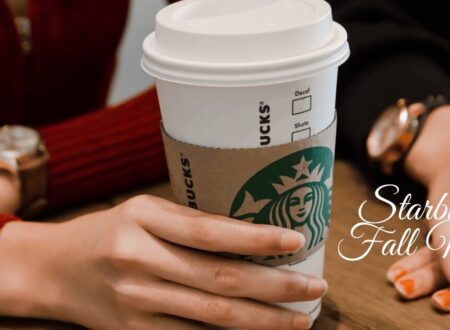 Person holding a Starbucks coffee cup on a table, representing the Starbucks Fall Menu.